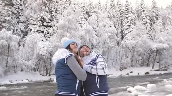 幸福的恋人在一条山河的岸边欣赏冬天的风景视频的预览图