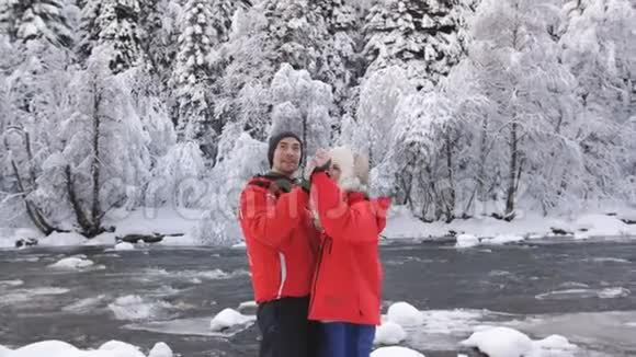 一对相爱的情侣在一条山河的河岸上享受着冬天的风景和拥抱视频的预览图