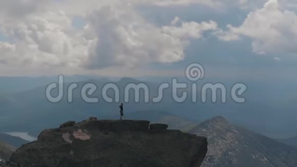 一位男性登山者站在山顶上快乐地举起双手的空中剪影视频的预览图
