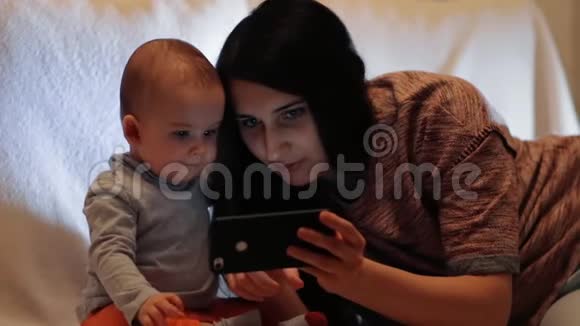 一位年轻漂亮的母亲在智能手机屏幕上向儿子展示了一些东西孩子看着智能手机视频的预览图