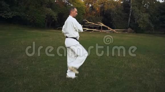 卡拉提卡他穿着和服的人踢腿早上在城市公园的空地上表演空手道视频的预览图