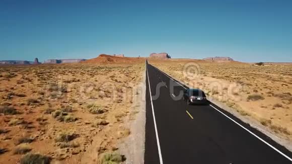 美丽的空中拍摄的银色汽车驾驶着惊人的美国沙漠道路向山区纪念碑谷视频的预览图