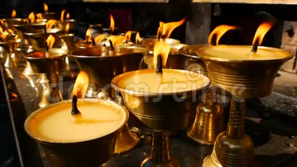 在寺庙里烧蜡烛观看金色闪亮的碗与燃烧的油烛火焰崇拜视频的预览图