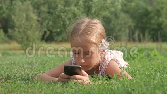 孩子用手机躺在绿草中视频的预览图