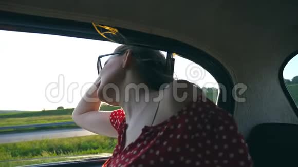 年轻迷人的女孩从窗外探出老式汽车在夏天享受骑马太阳在背景下闪耀视频的预览图