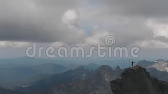 一名男子站在山顶胜利地举起双手欣赏美丽的景色视频的预览图