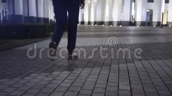 男人的双腿在市中心的夜城里行走视频的预览图
