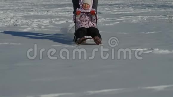 妈妈推着雪橇后面有一个小女儿一个三岁的小女孩和妈妈一起走视频的预览图