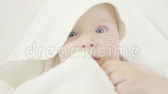 可爱的小宝宝洗完澡后裹上毛巾用蓝色的眼睛闭上肖像不可抗拒的样子视频的预览图
