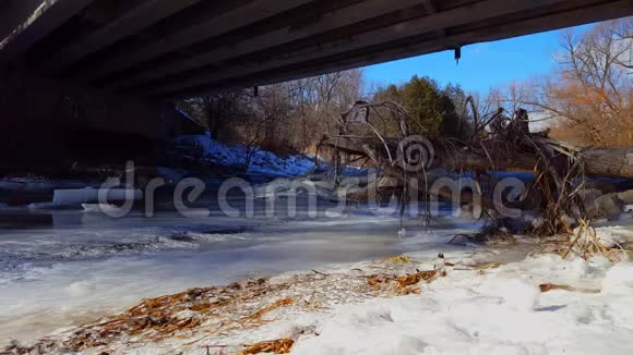 冬天在一座桥下结冰的河路桥下冰河水流视频的预览图