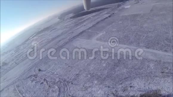 一架悬挂式滑翔机在冰雪覆盖的冬季草地和森林上空起飞视频的预览图