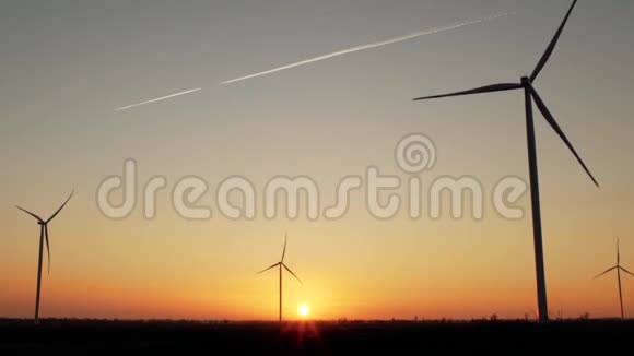 在美丽的夕阳下风力涡轮机在天空中飞行留下一条小径视频的预览图