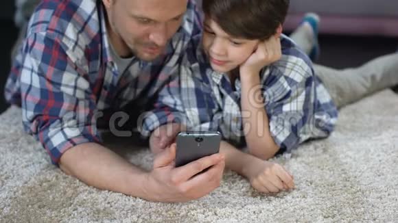 父亲在智能手机上展示儿子有趣的应用程序花时间在一起视频的预览图