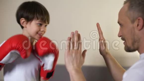 可爱的孩子和他的教练一起练习拳击和父亲一起玩运动视频的预览图