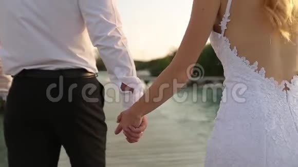 镜头跟随新娘新郎在豪华度假村桥上的平房附近沿着海岸线走向仪式视频的预览图