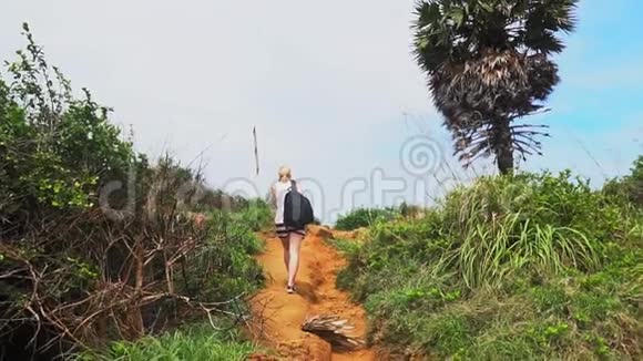 在热带岛屿上旅行一个女孩爬上山坡去看海景视频的预览图