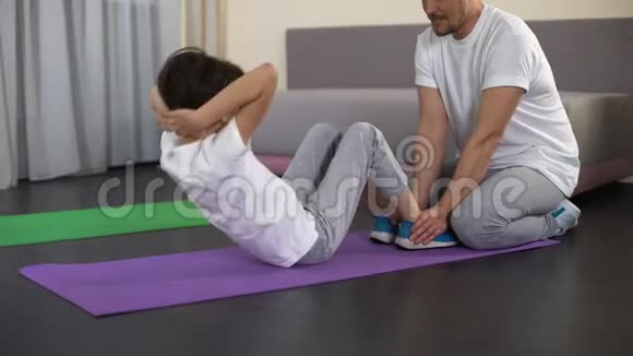 爸爸训练男孩子在家做仰卧起坐积极休闲健康生活方式视频的预览图