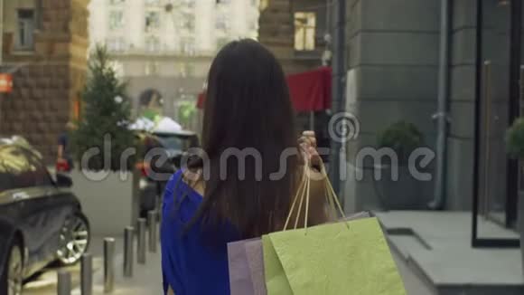 优雅的女人带着购物袋走在街上视频的预览图
