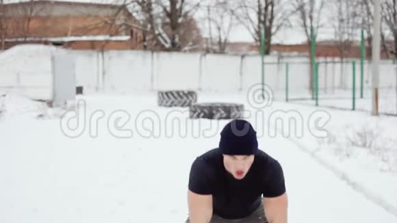 一个男人把一个橡胶轮胎扔到自己身上一个男人在冬天做交叉运动视频的预览图
