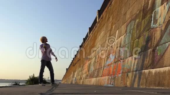 快乐的人在邋遢的河岸墙上扔一个球视频的预览图