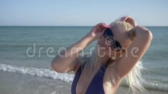 戴眼镜的快乐女人在旅行时在海滩上散步时做空中亲吻视频的预览图