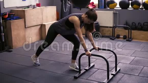 漂亮的活泼的黑发女孩在健身房里用俯卧撑做俯卧撑在坚固的武器和核心上工作健康视频的预览图