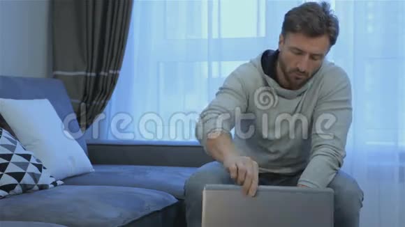 男人在家里打开笔记本电脑视频的预览图