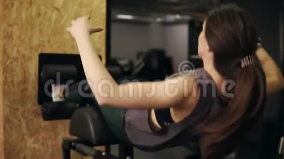 强壮的运动型女孩有运动的身体她的腹肌和核心肌肉使用特殊的健身器材叫做腹部长凳视频的预览图