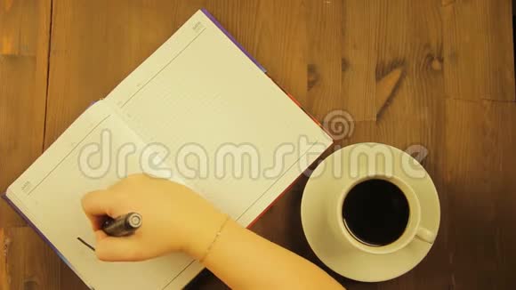 女孩在日记里用黑色记号笔写爱的字喝咖啡视频的预览图