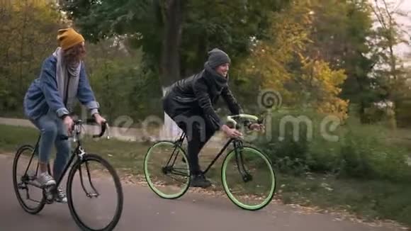 年轻的时髦夫妇骑着徒步自行车在公园里骑自行车两个年轻人在一起很开心视频的预览图