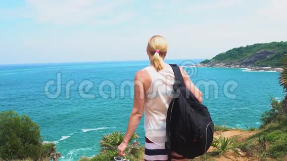 旅行者女孩看着悬崖边上美丽的海景视频的预览图