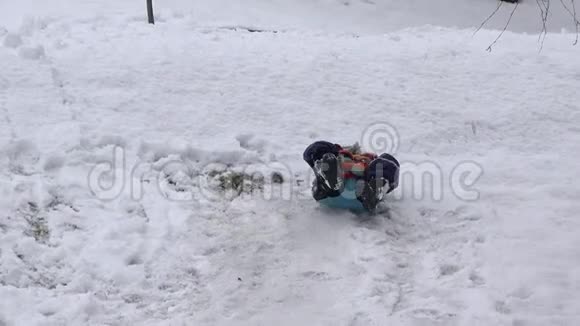 雪橇上可爱的孩子雪地上跌倒翻滚的孩子冬季运动意外视频的预览图