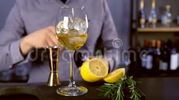巴尔曼把一些起泡葡萄酒从一个瓶子倒入一个酒杯与冰和白酒烹饪酒精鸡尾酒双手并拢视频的预览图