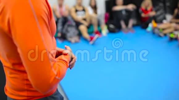 穿着橙色服装的教练在健身房训练时打手势视频的预览图
