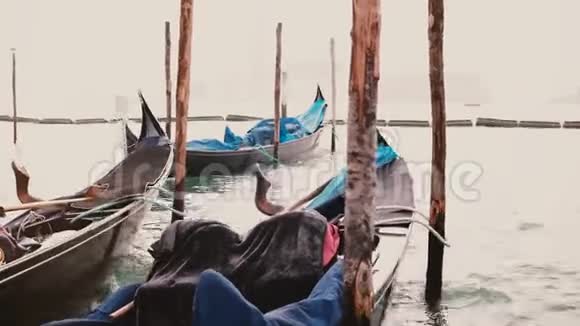 在威尼斯码头美丽的传统贡多拉船的特写镜头雨罩在巨浪上剧烈摇晃视频的预览图