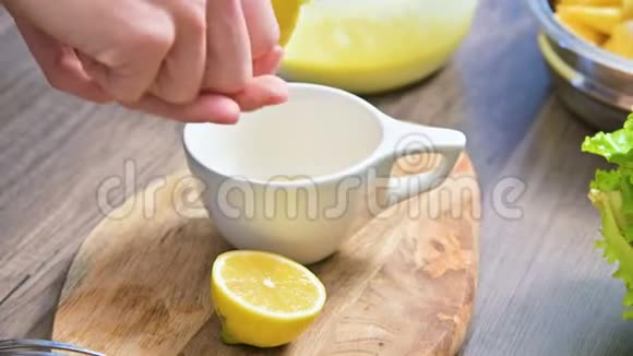 在家庭厨房的切割板上特写的女性双手捏着杯子里的柠檬视频的预览图