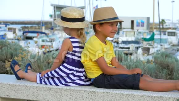 小男孩和小女孩坐在码头游艇俱乐部视频的预览图