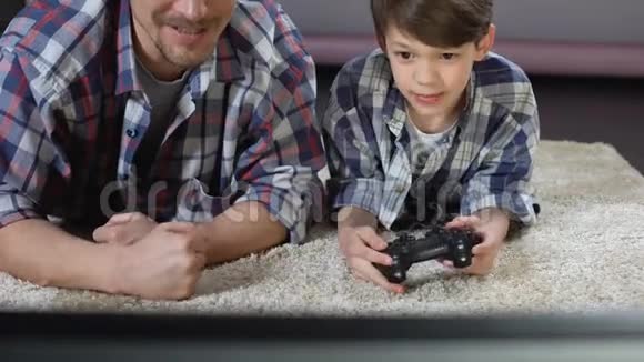 男人支持他的小儿子在家玩电子游戏家庭关系视频的预览图