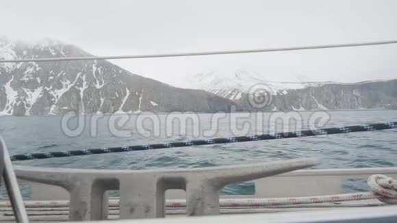 从蓝色海浪的帆船上看到的雪山和悬崖景观视频的预览图