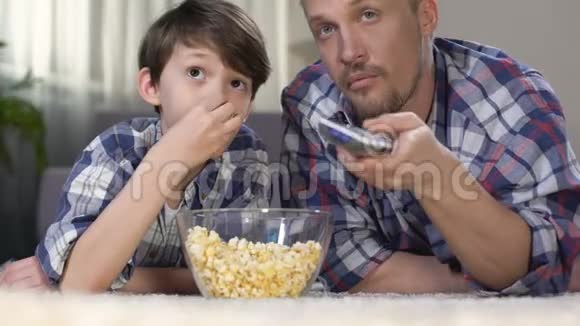 男性公司花时间一起看电视和吃爆米花父亲视频的预览图
