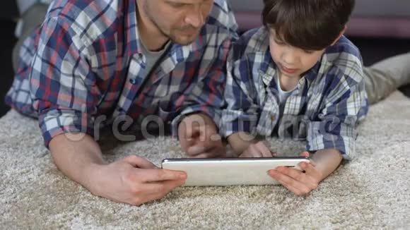 爸爸和儿子学习如何使用新平板电脑现代技术亲密视频的预览图