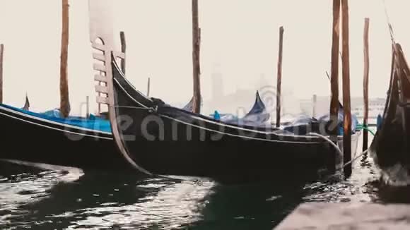 在意大利威尼斯雾蒙蒙的码头上美丽的传统的空船坞用雨罩在波浪上摇摆视频的预览图