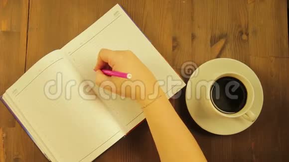 女孩在日记里用一支粉红色的毡尖笔和喝咖啡来写爱这个词时间跨度视频的预览图