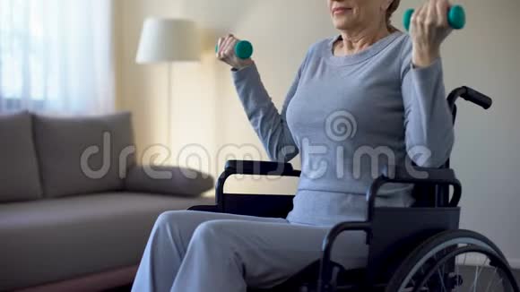 坐轮椅的老年妇女举起哑铃在家做运动康复视频的预览图