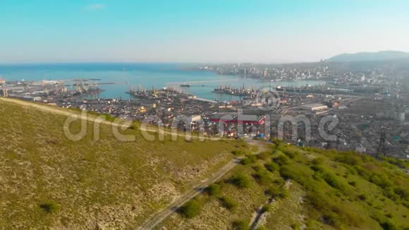 一名游客坐在山上进行四架直升机飞越从一架无人机Novorossiysk港口向Novorossiysk市射击视频的预览图