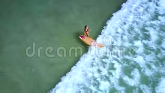 女孩拿着冲浪板克服泡沫海浪视频的预览图