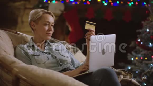 短头发的女人在圣诞夜使用笔记本电脑和信用卡在网上购物视频的预览图