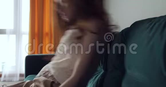 红发疲惫的女人在家里摔在沙发上头疼视频的预览图