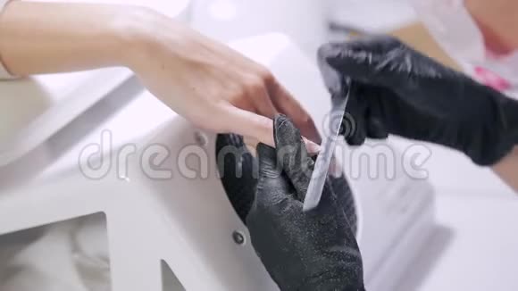 戴手套的美甲师在涂胶前用指甲锉钉客户视频的预览图