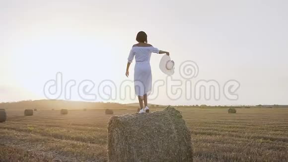 意大利托斯卡纳的一个年轻女孩站在干草堆上在蓝色的背景下举起和放下手臂视频的预览图